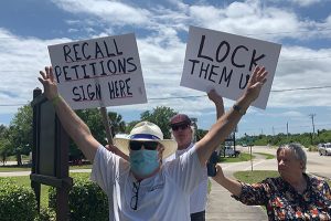 Councilman Damien Gilliams poses with signs at Riverview Park in Sebastian, Florida.