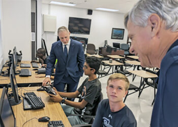 SRHS NJROTC Cadets Devon Desai (seated left) and Preston Kross (seated right) discuss the benefits of flight simulator software with Peter Petrelis (far right) and Jay Rinchak (far left).