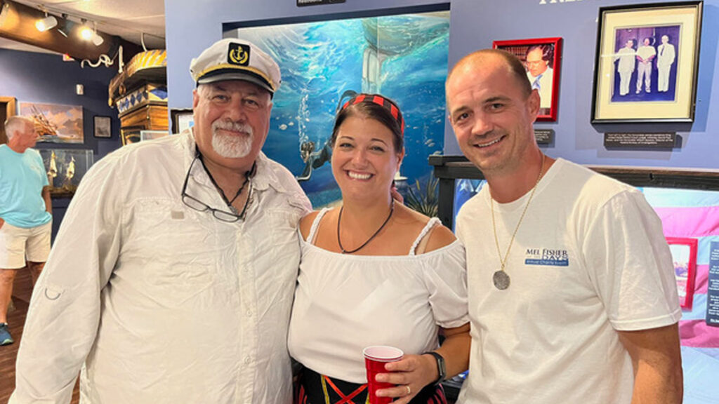 Vincent Trotta, left, Captain of the Mel Fisher’s Treasures company search and recovery vessel “DARE,” poses with Mel and Deo Fisher’s granddaughter Nichole Johanson and her husband James, in Sebastian, FL, during a Mel Fisher Days event. (Photo Credit: Jim Wilson)